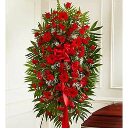 Tall standing spray of red flowers with a red ribbon