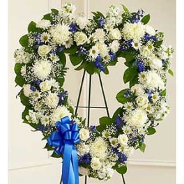 Heart-shaped floral wreath with white and blue flowers on a stand