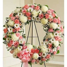 Pink and white floral wreath on a black easel with a pink ribbon bow