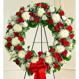 Red and white floral wreath on a black easel with a red bow
