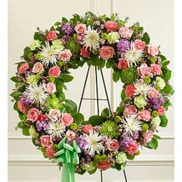 Heart-shaped floral wreath with pink, purple, and white blooms on an easel