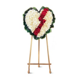 Heart-shaped standing floral tribute with white flowers and red roses on an easel
