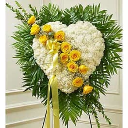 Heart-shaped white floral spray with yellow roses on a stand