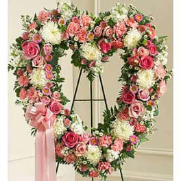 Heart-shaped floral wreath on an easel with pink and white flowers