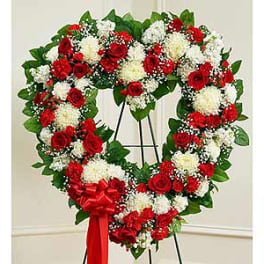 Heart-shaped floral wreath of red and white flowers on an easel