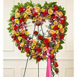 Heart-shaped floral wreath on a stand with a pink ribbon