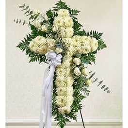 White floral standing spray with a ribbon on a cross-shaped frame