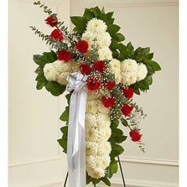 Cross-shaped floral spray with red roses and white flowers on a stand