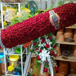Large red floral spray with roses and white ribbon on a stand