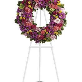 Circular floral wreath on a white easel with purple, pink, and yellow flowers