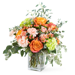 Orange and peach roses with pink carnations in a glass vase