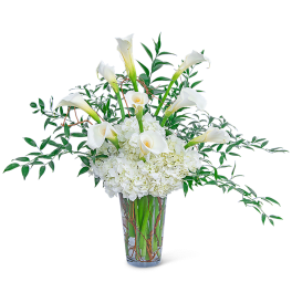 White calla lilies and hydrangeas in a clear glass vase
