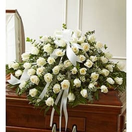 White rose casket spray with ribbon on a wooden coffin
