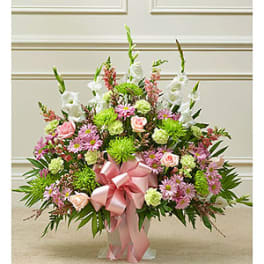 Large pink and white floral arrangement with a pink ribbon in a vase