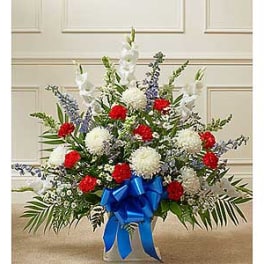 Red and white floral spray with a blue ribbon in a vase