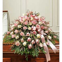 Large pink and white rose spray with satin ribbons on a casket