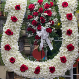Large floral wreath of white chrysanthemums with red roses and a white bow