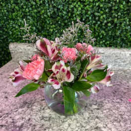 Pink and white flowers arranged in a clear glass bowl vase