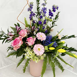 Mixed bouquet of pink roses, lilies, and purple flowers in a pink vase