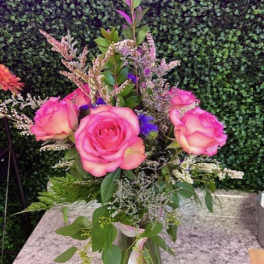 Pink roses arranged in a clear vase with mixed filler flowers