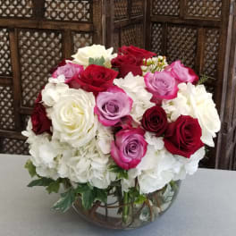 Bouquet of red, pink, and white roses in a glass bowl vase