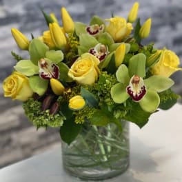 Yellow roses and orchids arranged in a glass vase