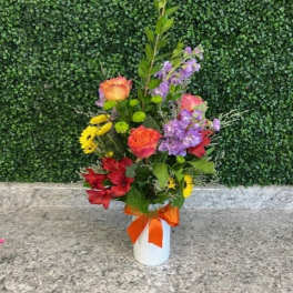 Mixed bouquet in a white vase with an orange ribbon