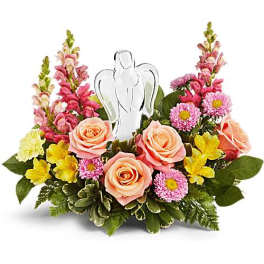 Low arrangement of peach roses and mixed pink and yellow flowers with a glass angel figurine in the center