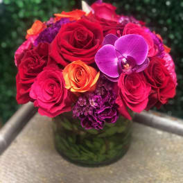 Bouquet of red and pink roses with a purple orchid in a glass vase