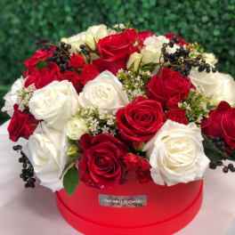 Red and white roses arranged in a red round box