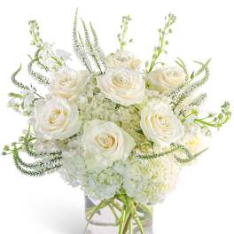 White roses and hydrangeas in a clear glass vase