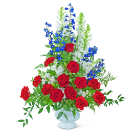 Red roses and carnations with blue and white flowers in a white vase