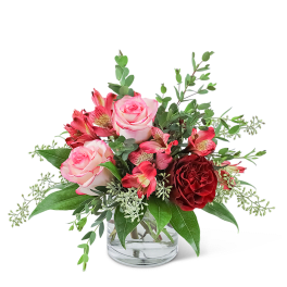 Pink and red roses in a clear glass vase with greenery