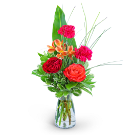 Mixed bouquet of roses, carnations, and orange blooms in a glass vase