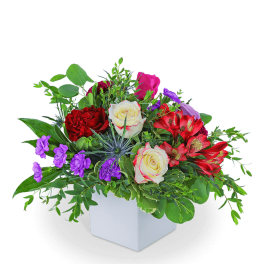 Mixed bouquet of roses, alstroemeria, and purple flowers in a white cube vase