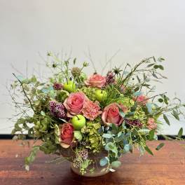 Pink roses in a low bowl with greenery and green apples
