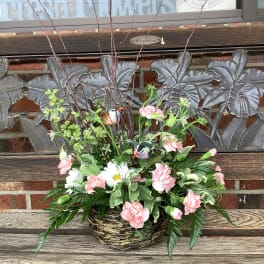 Basket arrangement with pink carnations, white daisies, and bird decorations