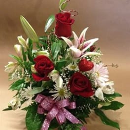 Red roses and white lilies arranged with a pink ribbon bow