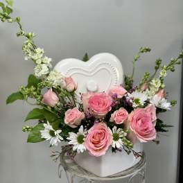 Pink roses and white daisies arranged in a white heart-shaped vase
