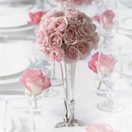 Pink rose bouquet in a tall silver vase on a white table