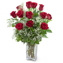 Red roses arranged in a clear glass vase with white filler flowers
