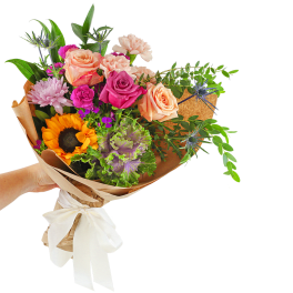 Hand-tied bouquet of mixed roses, carnations, and a sunflower in brown paper