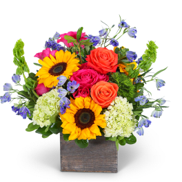 Bright mixed bouquet in a square wooden vase with sunflowers and roses