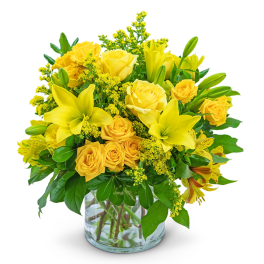 Yellow roses and lilies arranged in a clear glass vase