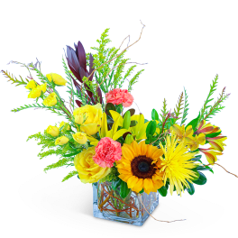 Bright mixed bouquet in a clear square vase with sunflowers and yellow roses