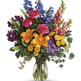 Colorful bouquet of roses, lilies, and snapdragons in a glass vase