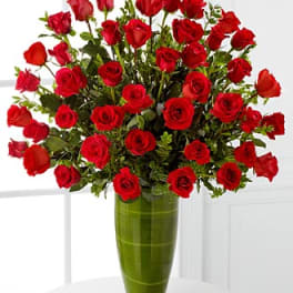 Bouquet of red roses in a tall green glass vase