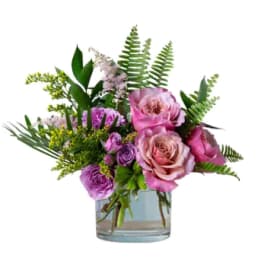 Pink and purple roses arranged in a clear glass vase