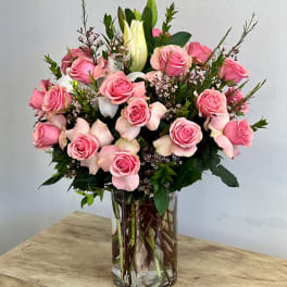 Pink roses and white lilies arranged in a clear glass vase