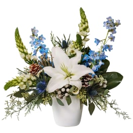 White lily arrangement with blue flowers in a white vase